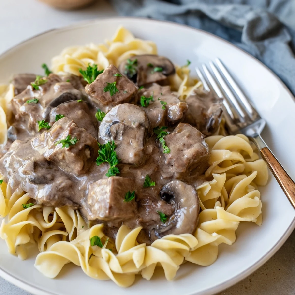 Creamy slow cooker beef stroganoff served over tender egg noodles, garnished with parsley.  