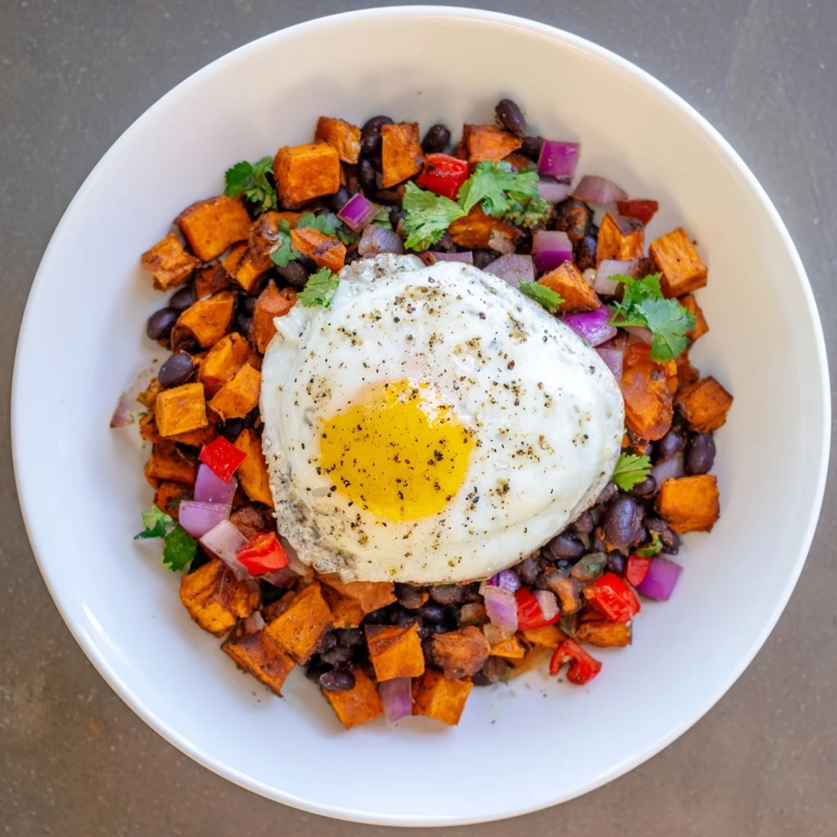 Golden-hued Sweet Potato & Black Bean Breakfast Hash, topped with perfectly cooked eggs and fresh cilantro.