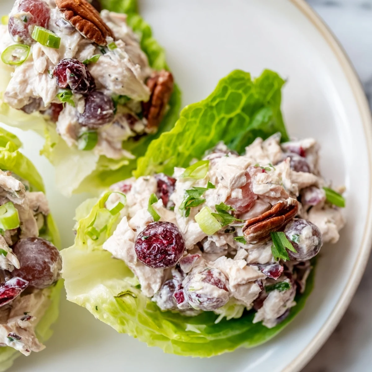 Festive Chicken Salad Cups, a colorful appetizer with grapes and pecans, nestled in fresh, green lettuce.