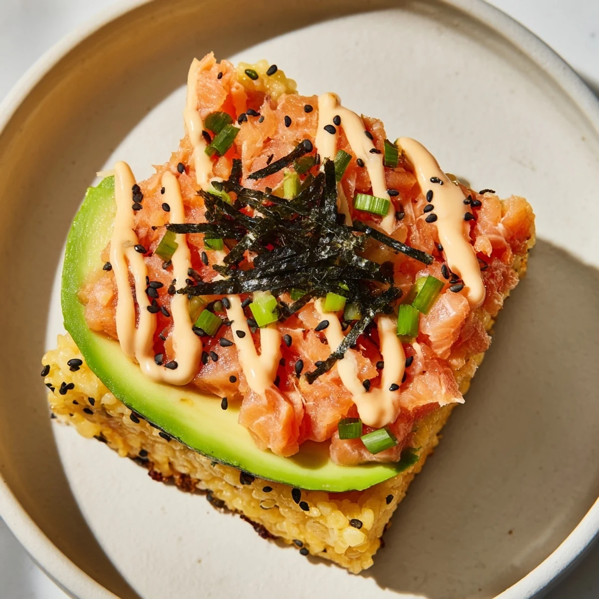 A close-up shows layers of the delicious Crispy Rice Salmon Stack with creamy avocado and sauce.