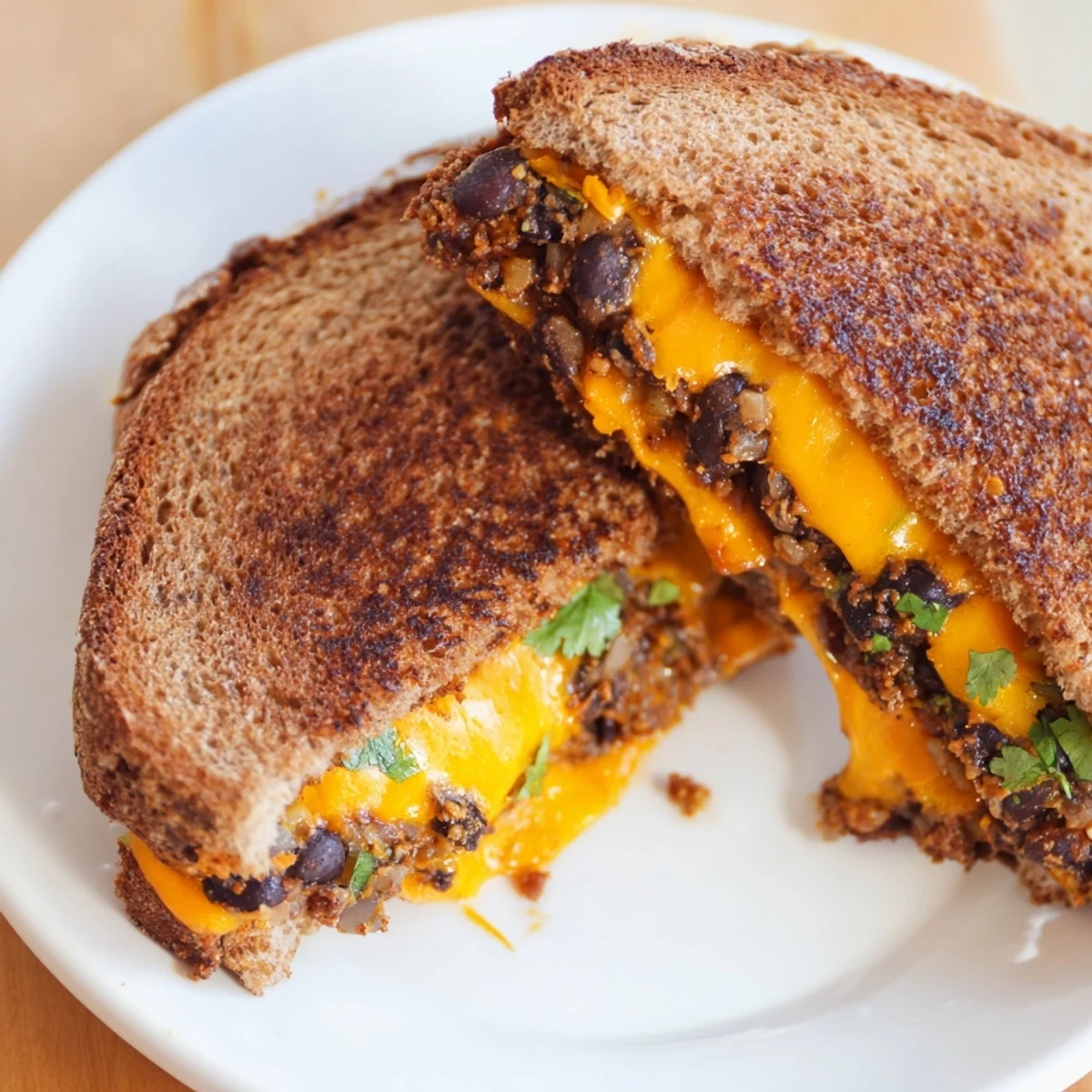 A close-up of a golden-brown Black Bean Grilled Cheese, oozing melted cheese, ready to eat.
