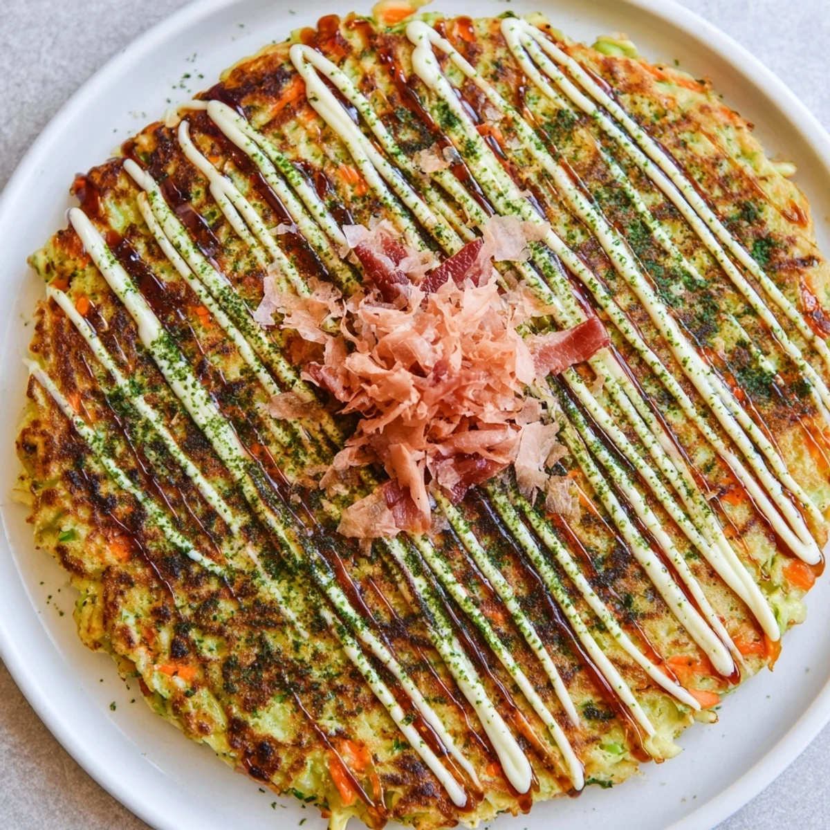 Golden-brown Japanese Okonomiyaki Pancakes sizzling on a griddle, topped with creamy mayo and dancing bonito flakes.  