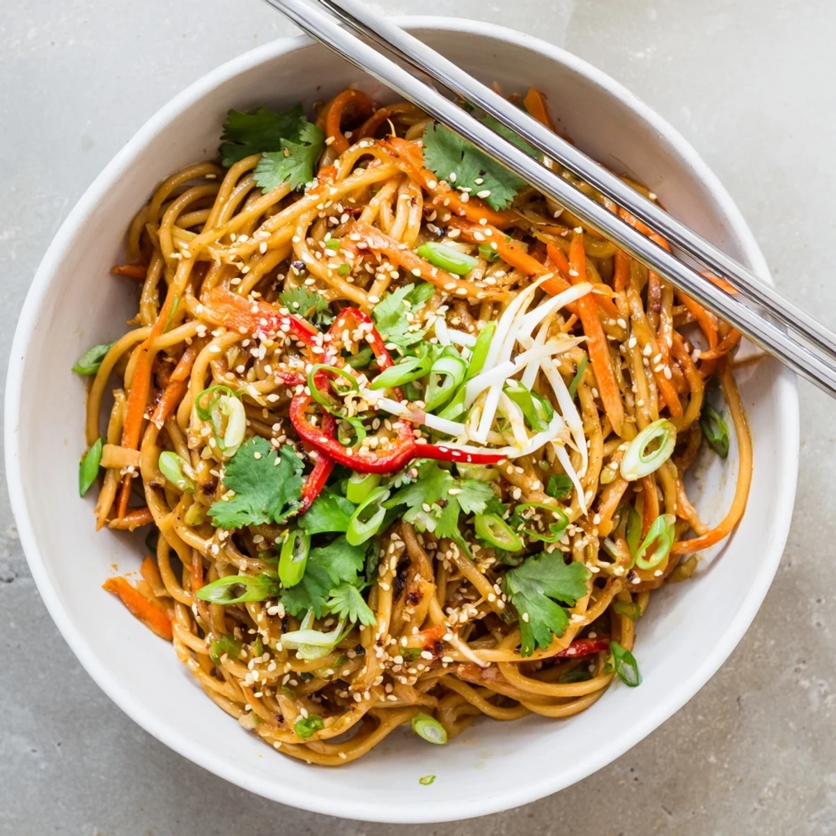 Close-up of glossy Asian Garlic Noodle Bowl tossed in savory garlic butter sauce, topped with fresh bean sprouts and carrots.  