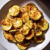 A close-up of beautifully browned zucchini chips, ready to be enjoyed with a dipping sauce.