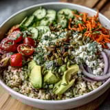 A vibrant simple grain bowl with fluffy quinoa, grilled chicken, avocado, cherry tomatoes, and pumpkin seeds, drizzled with lemon dressing.