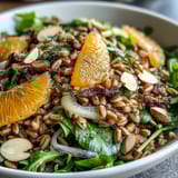 A vibrant Farro Salad Bowl with Fennel, Oranges & Almonds, featuring chewy grains, crisp slices, and toasted nuts on a bed of greens.  