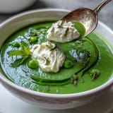 Spring pea soup showing fluffy whipped ricotta and bright mint oil finish.