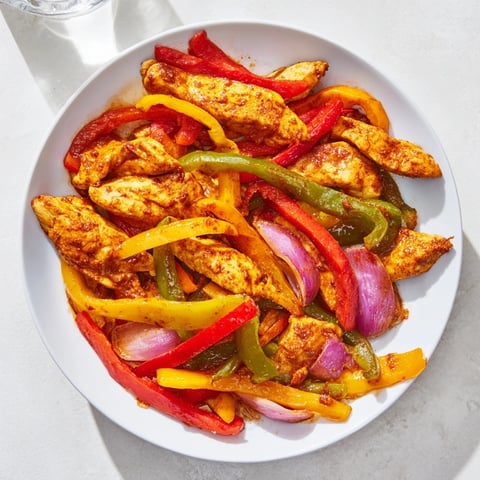 Sheet-pan chicken fajitas with sizzling chicken and colorful peppers, ready to serve with tortillas.