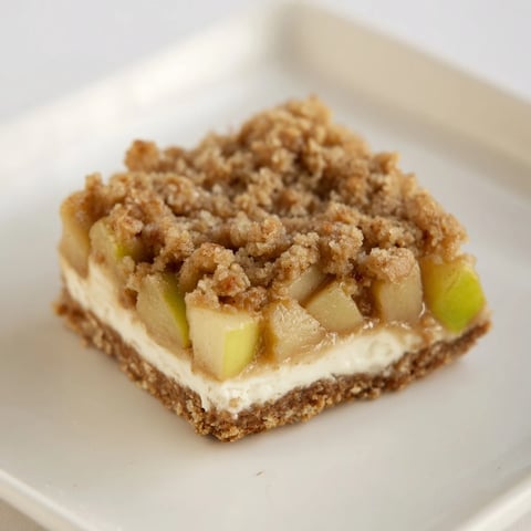 Warm, golden-brown Apple Crisp Cheesecake Bars offer layers of sweet apple and creamy cheesecake.