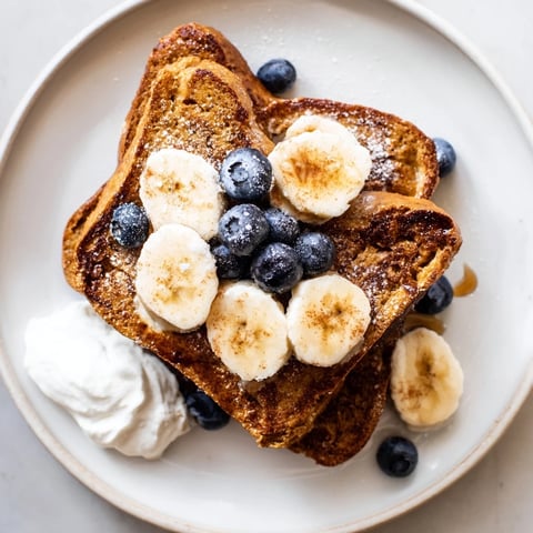 Golden, custardy Protein French Toast, topped with fresh berries, perfect for a hearty breakfast.