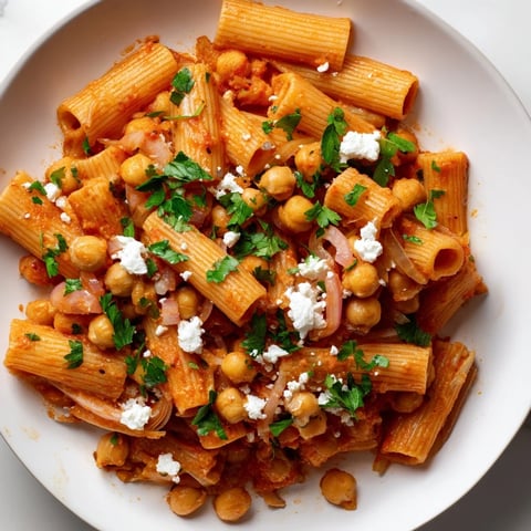 Steaming bowl of Harissa Chickpea Pasta, a vibrant Mediterranean meal with creamy chickpeas and herbs.