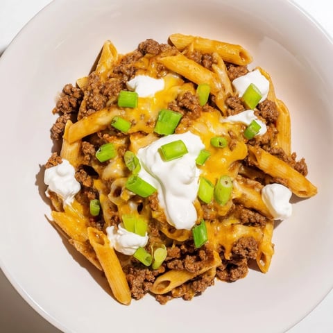 A steaming pot of one-pot taco pasta, topped with melted cheese and fresh green onions.