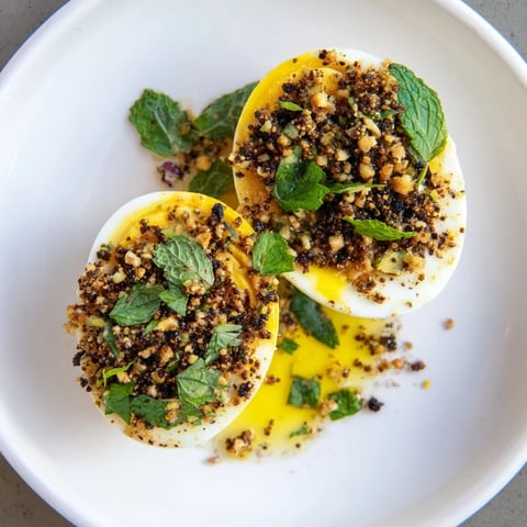 Golden, halved Dukkah-Spiced Eggs are piled high, topped with fresh herbs and a fragrant dukkah spice blend.