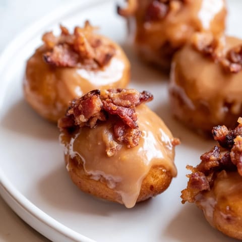 Bite-sized maple bacon donut holes gleam with icing, ideal for cozy brunches.  