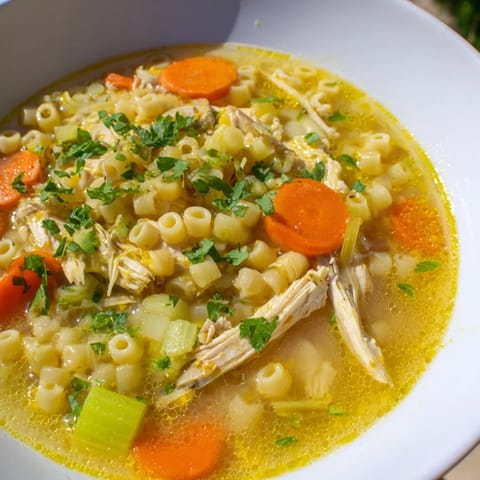 Golden chicken and ditalini pasta swim in a vibrant broth of this delicious Flu Fighter Soup, seasoned well.