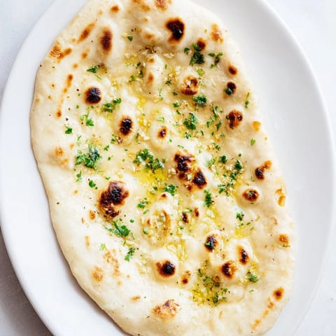 A stack of freshly cooked garlic naan, its surface glistening with melted garlic butter for a flavorful treat.