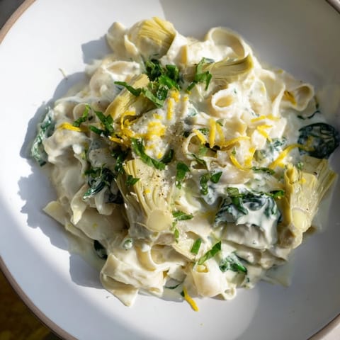 Lemony, creamy Creamy Lemon Artichoke Pasta topped with fresh herbs, ready for serving.