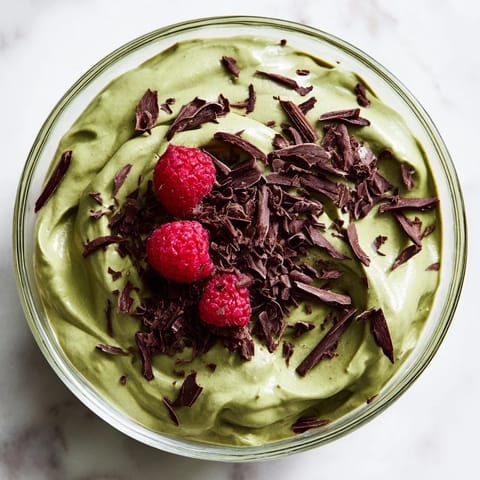 Smooth, dark-chocolate Avocado Pudding, topped with coconut whipped cream, ready to be devoured.