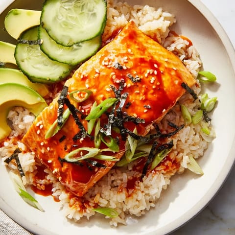 Beautiful, pan-seared Emily Mariko salmon bowl featuring glistening gochujang glazed salmon with fresh avocado.