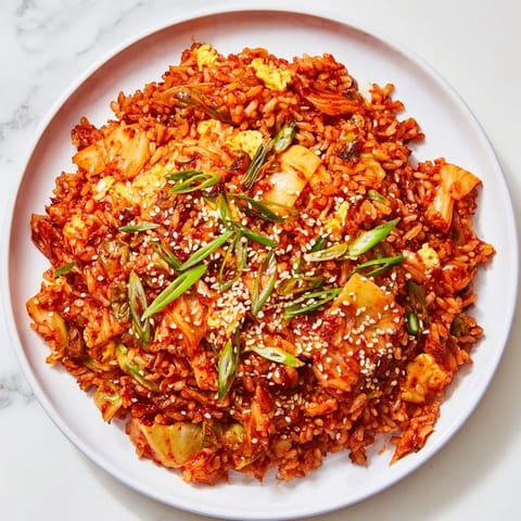 Steam rises from a bowl of Spicy Kimchi Fried Rice, garnished with green onions and sesame seeds, ready for a quick and flavorful dinner.