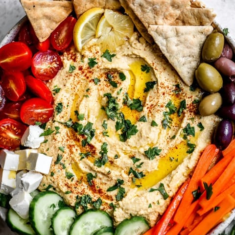 Colorful Middle Eastern Mezze Platter featuring tangy feta, warm pita triangles, and crisp cucumber and tomato slices.