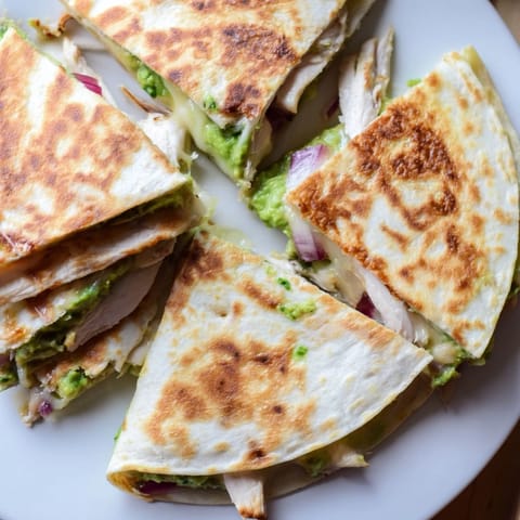 Grilled chicken and creamy avocado filling spilling out of a crispy tortilla.