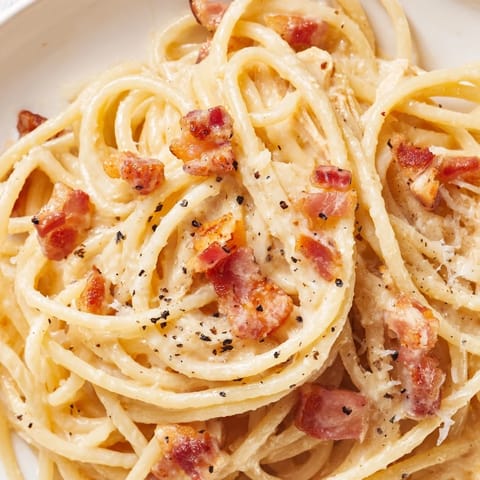 A close-up of creamy chicken carbonara with tender shredded chicken and crispy bacon in a silky Parmesan sauce.