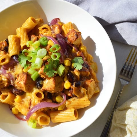 Golden, crispy chicken chunks rest in Crispy Chicken Burrito Pasta, garnished with fresh cilantro and served with lime wedges.