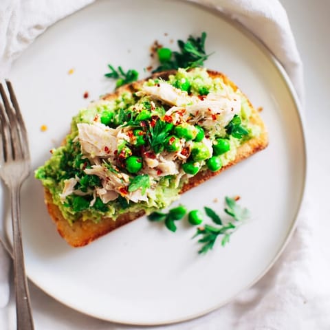 Savory Smashed Pea & Chicken Toast on rustic bread, garnished with mint and feta for a vibrant, protein-packed meal.  