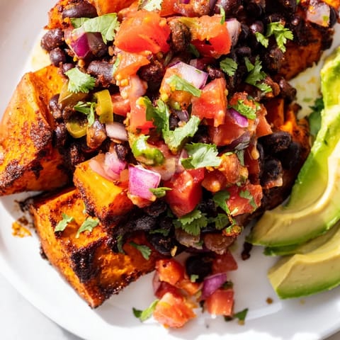 Warm, roasted sweet potatoes filled with seasoned black beans and vibrant tomato salsa garnish.  