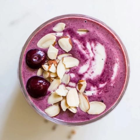 Thick, frosty Cherry Almond Smoothie in a mason jar topped with a drizzle of almond butter, perfect for a creamy breakfast or snack.