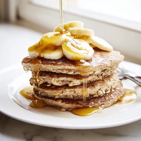 Golden-brown Banana Oat Pancakes served warm on a rustic plate, sprinkled with cinnamon and ready to enjoy.  