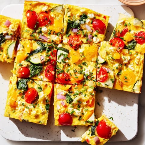 Golden-brown squares of High-Protein Sheet Pan Eggs With Cottage Cheese and Veggies, garnished with fresh chives and served warm.