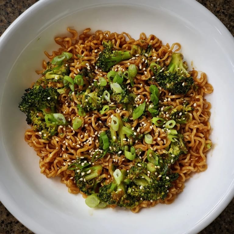 Golden-brown Ramen Noodle Stir-Fry Remix, ready to eat, topped with sesame seeds and green onions.