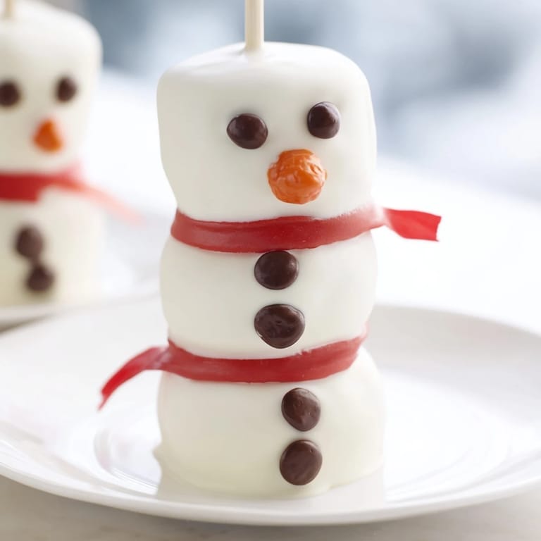 Festive Express Snowman Marshmallow Pops with edible faces and scarfs, ideal for a joyful holiday dessert.