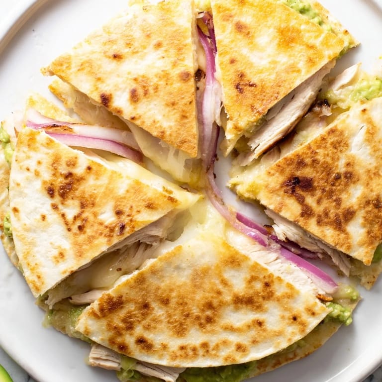 A fresh Chicken Avocado Quesadilla served with lime wedges and cilantro for dipping.