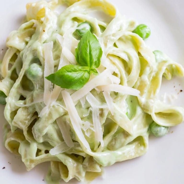 Steaming Creamy Green Pea Alfredo served in a white bowl, paired with a crisp green salad on the side.