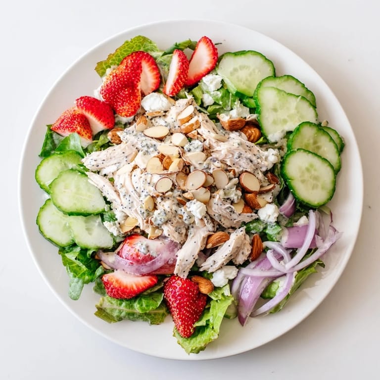 Colorful Strawberry Poppy Seed Chicken Salad served in a white bowl, perfect for a light lunch with crumbled feta.  