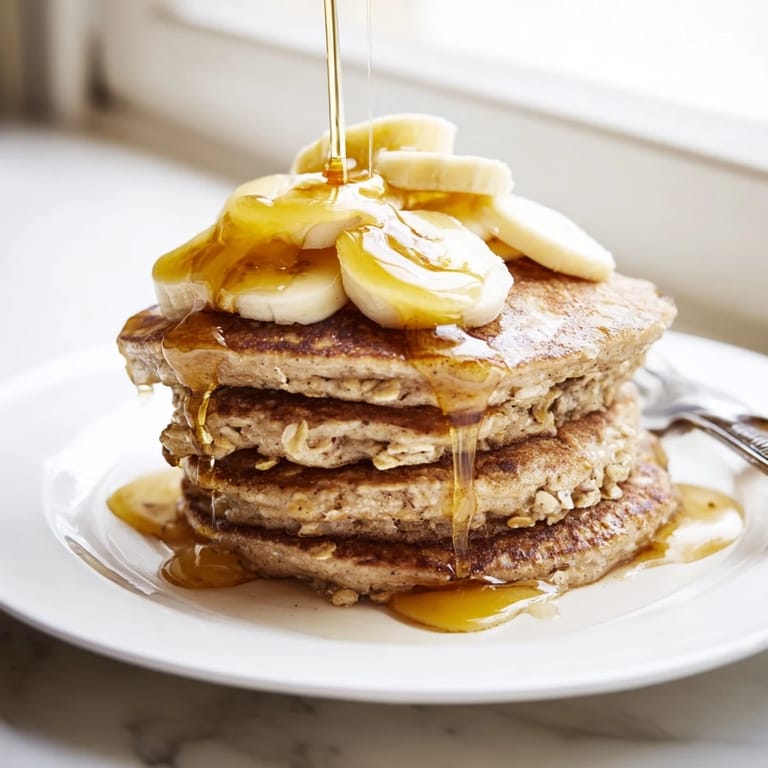 Golden-brown Banana Oat Pancakes served warm on a rustic plate, sprinkled with cinnamon and ready to enjoy.  