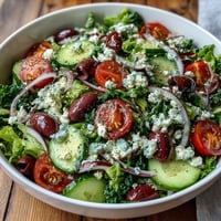 Crisp spring mix, cherry tomatoes, cucumber, and feta tossed in a zesty Greek dressing in this Mediterranean Green Salad Bowl.  