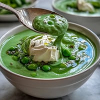 Vibrant spring pea soup, creamy ricotta swirl, fresh mint oil drizzle.